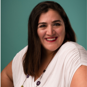 Photo of woman with long brown hair wearing a white top, smiling
