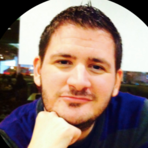 Photo of man with short brown hair looking directly at camera with hand under chin